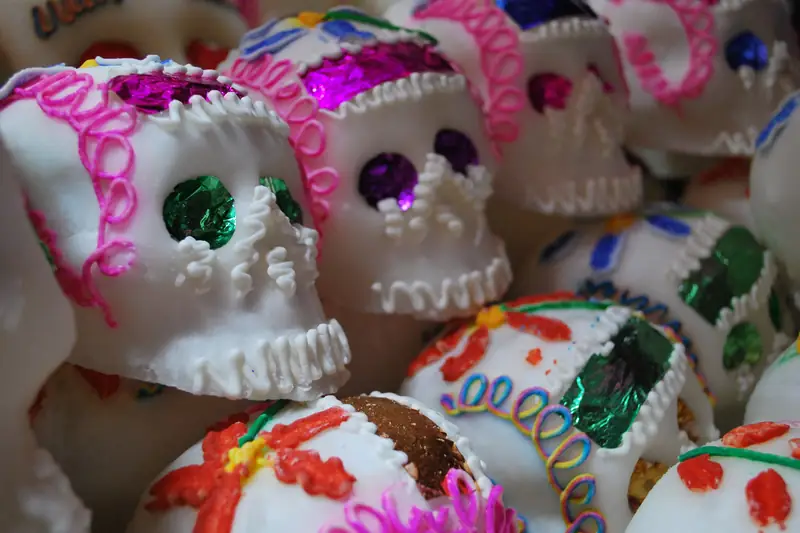 Close-up of white sugar skulls decorated with pink and blue icing and shiny foil eyes