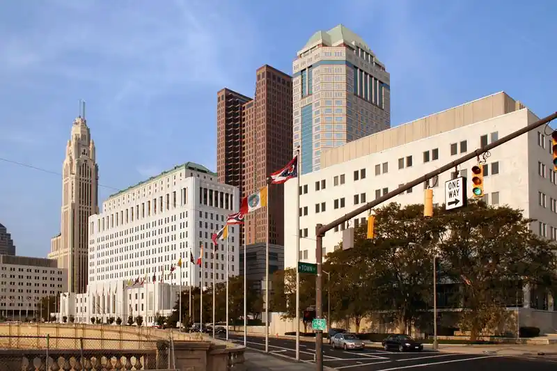Downtown Columbus office towers along a riverside street under a blue sky