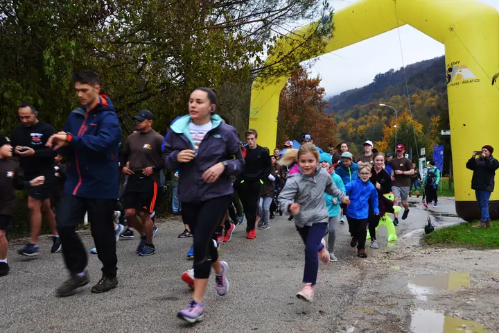 Adults and children setting off on a fall turkey trot fun run under a yellow inflatable arch