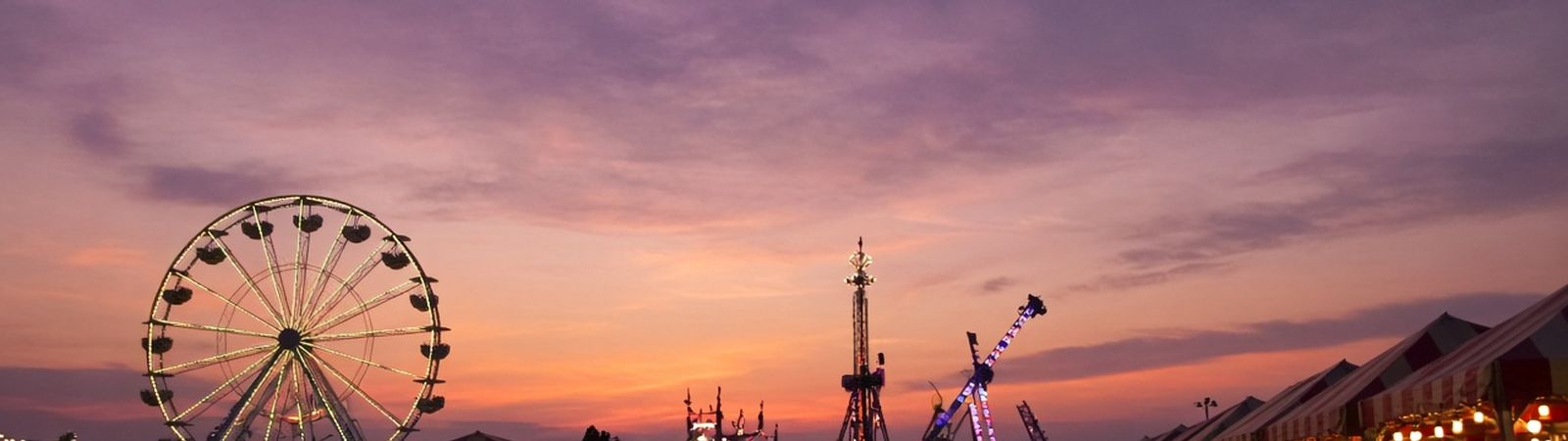 Illustration of a fair midway at dusk with a lit Ferris wheel, carnival rides and striped food stands